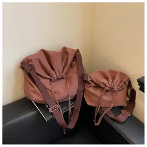 Vue détaillée du sac bandoulière marron à cordon, tissu souple et sangle réglable.