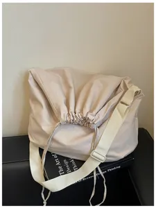 Vue détaillée du sac à bandoulière minimaliste beige à cordon avec une large sangle élégante.