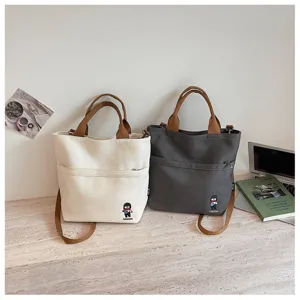 Sac bandoulière en toile épaisse style coréen avec poignées marron et poche avant, style quotidien.