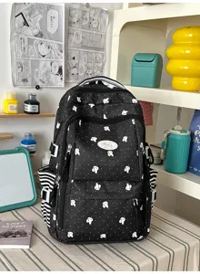 Gedetailleerd uitzicht van de zwarte rugzak met stippen en een schattige patch en zijvakken.