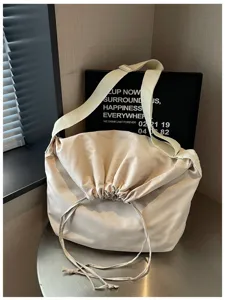 Vue détaillée du sac messager beige à cordon de serrage, tissu doux et large bandoulière.