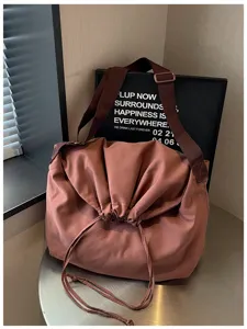 Vue détaillée du sac bandoulière souple de couleur unie, affichant un tissu doux et cordon.