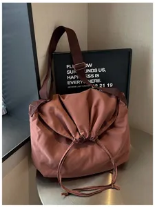 Vue détaillée d'un sac bandoulière à cordon de niche, grande capacité style messager uni.
