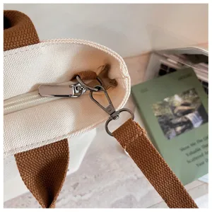 Détail du sac cabas en toile avec fermeture éclair en métal et boucle de sangle.