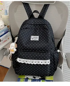Schattige zwarte stippen rugzak met witte kantrand en puppyhanger voor schoolgebruik.