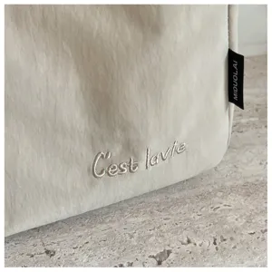 Detailansicht der beigen Segeltuchtasche mit feiner Stickerei und edlem seitlichem Markenlabel.