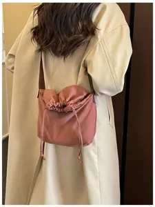 Vue rapprochée du sac porté rose à cordon, montrant une texture souple et un style décontracté.