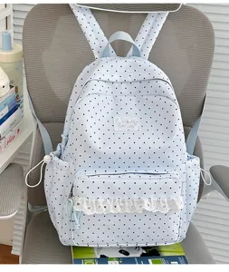 Detailopname van de schattige lichtblauwe rugzak met polkadots en delicate witte kanten rand.