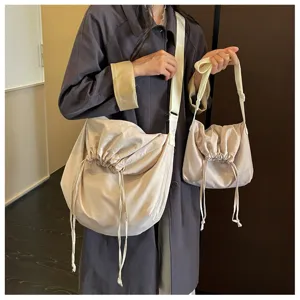Vue détaillée de la scène montrant des sacs à bandoulière beiges à cordons larges.