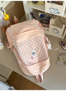 Gedetailleerd uitzicht op de roze geruite rugzak met schattig konijnenborduurwerk op voorzak.