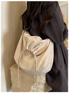 Vue de détail d'un sac porté épaule besace beige minimaliste avec cordon de serrage souple.