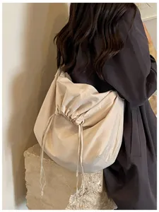 Gros plan détaillé d'un sac bandoulière souple beige minimaliste avec cordon de serrage.