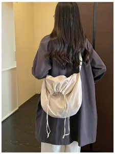 Vue rapprochée du sac bandoulière minimaliste à cordon, porté de manière décontractée à l'intérieur.