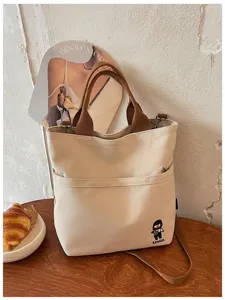 Vue détaillée du sac cabas en toile beige avec anses marron et broderie mignonne.