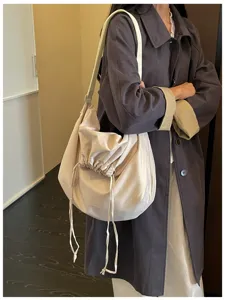 Vue détaillée d'un sac souple beige avec cordon de serrage porté par un mannequin.