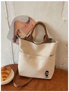 Vue détaillée du sac cabas en toile épaisse, doté d'une poche avant et de poignées marron.