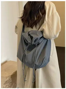 Vue rapprochée du sac bandoulière gris en nylon avec cordon et détails de conception souple.