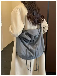 Vue détaillée élégante du sac bandoulière gris souple à cordon porté par le mannequin.