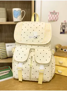 Detailgezicht van gele polkadot rugzak met ruitjesrand en schattige konijnenpatch erop.