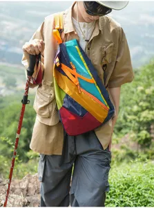 Detail shot of a vibrant color-blocked sling bag worn during outdoor hiking and adventures.