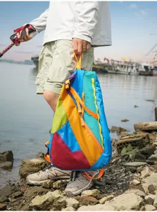 Colorful outdoor backpack detail view showing vibrant multi-panel design and sturdy orange straps.