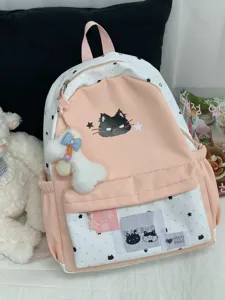 Detail van roze-witte canvas rugzak met sterrenmotief, zwarte kat en pluche sleutelhanger