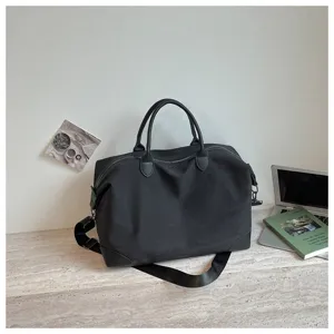 Minimalistische zwarte oxford stoffen reistas met schouderriem voor korte reizen.