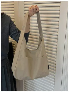 Detailansicht einer Beigefarbenen Canvas-Schultertasche mit Fronttasche und Stickerei.