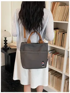 Gros plan détaillé sur le sac à bandoulière en toile avec une poche avant et des poignées.