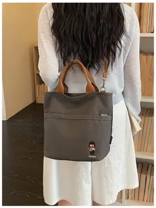 Vue détaillée du sac cabas fourre-tout en toile gris foncé avec anses marron et poche.