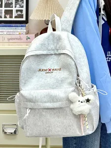 Detailansicht des lässigen hellgrauen Canvas-Rucksacks mit süßem flauschigen Anhänger und Kordeln.