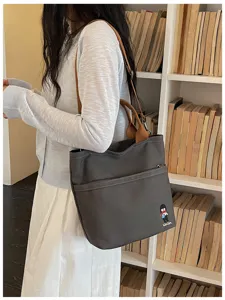 Sac à bandoulière en toile décontracté avec poche avant et poignées marron pour les cours.