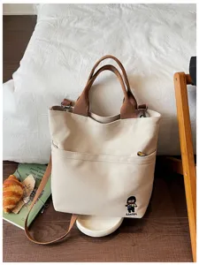 Détail du sac cabas en toile avec tissu épais, poche avant et jolie broderie.