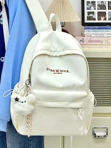 Detailansicht des minimalistischen weißen Rucksacks mit praktischer Vordertasche und Anhänger.