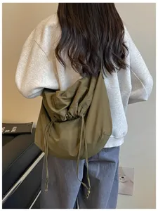 Vue détaillée du sac bandoulière souple vert olive à cordon, sac de transport quotidien en tissu.