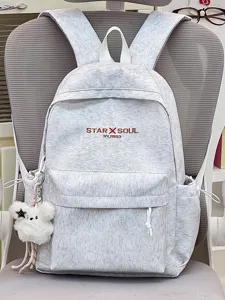 Nahaufnahme des hellgrauen Rucksacks mit Frontstickerei, Seitentasche und süßem Bärenanhänger.