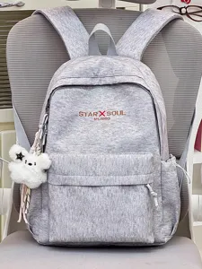 Detailansicht des grauen Stoffrucksacks mit praktischer Vordertasche und süßem Plüschanhänger.