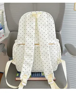 White and black polka dot student backpack detail view, casual school bag with adjustable straps.