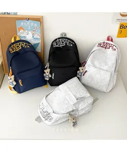 Detail shot of casual canvas backpacks in multiple colors with cute bear pendants and embroidery.