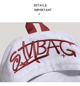 Close-up of casual grey backpack with red embroidered graffiti letters and carry handle.