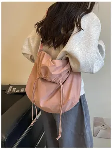 Vue détaillée du sac bandoulière rose style slouchy avec cordon, grande capacité.
