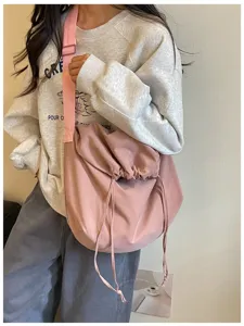Grand sac bandoulière rose en toile avec cordon coulissant, vue détaillée du port à l'épaule.