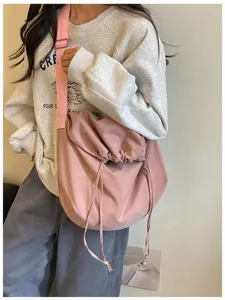 Vue détaillée d'un sac bandoulière rose à cordon coulissant, sac hobo souple unicolore.
