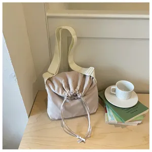 Vue détaillée du sac bandoulière uni avec cordon de serrage et sangle large ton neutre.