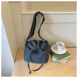 Vue détaillée du sac bandoulière gris foncé à cordon, en tissu souple avec sangle réglable.