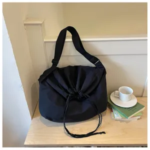 Vue détaillée du sac bandoulière noir décontracté à cordon, tissu souple et sangle réglable.