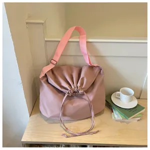 Vue détaillée du sac bandoulière rose souple avec cordon de serrage et large sangle tendance.