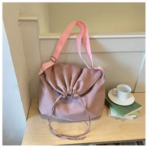 Sac bandoulière souple rose à cordon détail avec large sangle et ambiance quotidienne.