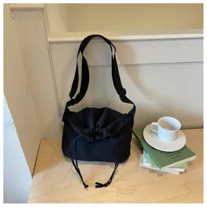 Vue détaillée du sac bandoulière noir à cordon dans un cadre de bureau lifestyle.