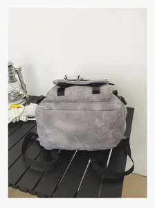 Vue de détail du sac à dos camouflage gris, avec rabat à double boucle et bretelles solides.